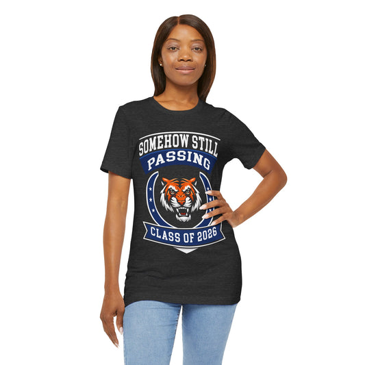 Somehow Still Passing — Funny Senior Tiger Tee (Class of 2026)